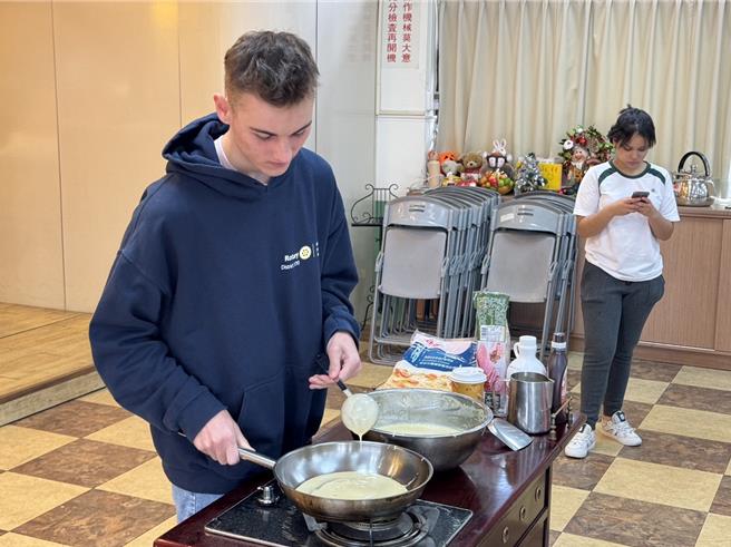 台中市侨泰高中23日与华山基金会、大里扶轮社合作，邀请大里区与南区7位独居长辈到侨泰校内咖啡厅用餐，法国交换生Antoine现场制作家乡美食可丽饼与长辈分享。（潘虹恩摄）