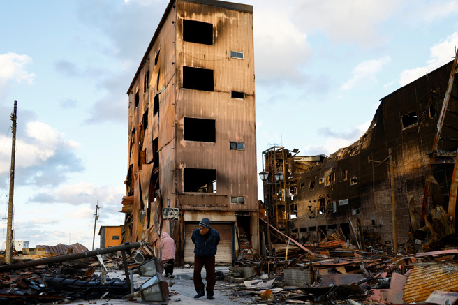 2024年1月4日，日本石川縣輪島市，一名男子走過地震後焚毀的朝市大道。（路透社）