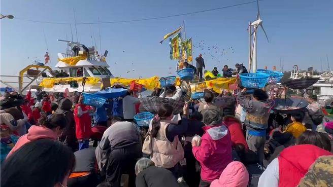 彰化縣線西鄉漁民黃超群訂造多時的的新船26日從宜蘭南方澳駛回線西塭仔漁港，新船進港時向岸邊聚集的群眾撒下總計1公噸的麻糬、包子、糖果及餅乾，場面熱烈。（孫英哲攝）