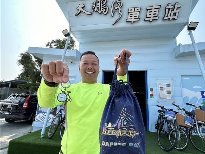大鵬灣單車站業者羅博原響應觀光署「16條多元路線踩點Go」送紀念幣活動，加碼送單車吊飾小禮，加上鵬管處也加送小提袋，讓騎大鵬灣路線的遊客可以一次領3份禮。（謝佳潾攝）