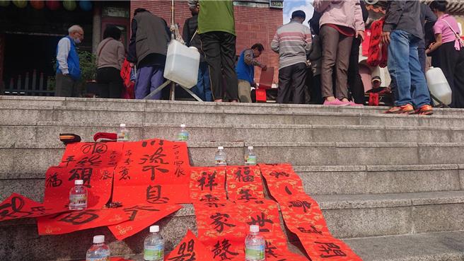 台南市北區大觀音亭27日舉辦春聯揮毫，廟前階梯成為晒春聯的最佳地點。（程炳璋攝）