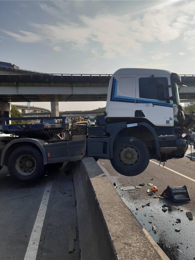 國道1號北向362.2公里處（鼎金系統交流道），今天下午發生48歲許姓男子駕駛聯結車，疑因操作不當失控自撞內側護欄，半截車頭、車身卡在護欄上，占據出口匝道內側交通，所幸許男未受傷，肇事原因警方深入調查中。（國道警方提供／林雅惠傳真）