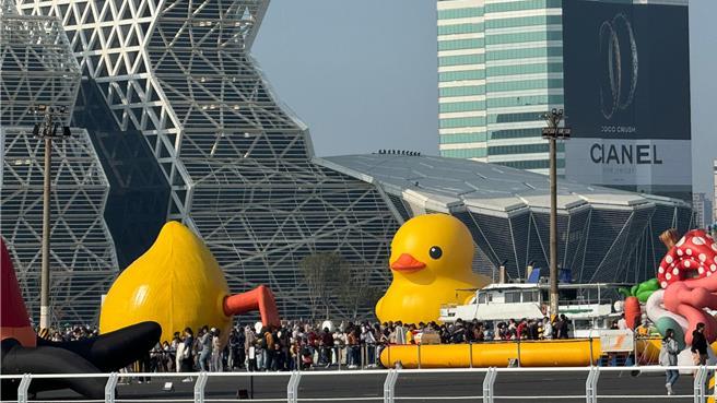 今天是黄色小鸭展出的首个平日，本报下午到爱河湾观察，虽然午后艷阳高照，但游客兴致不减，不乏家庭亲子、放寒假的学子，也有国外游客前来，大家争相跟小鸭拍照。（柯宗纬摄）