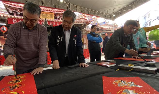 台中市樂成宮30日舉辦「春節揮毫贈春聯」活動，邀請知名書法家蕭世煌（左一）及立委黃國書（左三）帶頭陣現場揮毫，鄉親排隊索取春聯。樂成宮董事長何敏誠（左二）說，樂成宮春節期間將發放限量錢母。（陳淑芬攝）