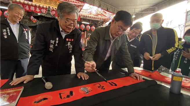 台中市樂成宮30日舉辦「春節揮毫贈春聯」活動，鄉親排隊索取春聯，書法家立委黃國書（前排左二）到場揮毫，樂成宮董事長何敏誠（前排左一）說，樂成宮春節期間將發放限量錢母。（陳淑芬攝）