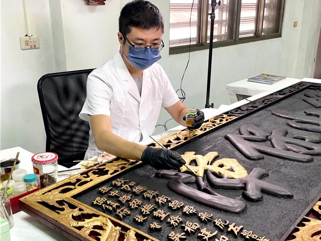 花蓮縣玉里鎮協天宮鎮宮之寶「後山保障」牌匾，立於光緒7年，迄今已有百年歷史，因香火煙燻覆蓋，彩繪層與貼金層出現裂痕，修復師細心的用棉花棒沾清潔溶液清除煙燻油汙。（花蓮縣文化局提供／羅亦晽花蓮傳真）