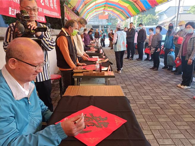 台中市议长张清照（左）31日在服务处前，举行书法老师挥毫写春联活动，张亲手写下「龙」字，预祝龙年大家龙腾虎跃、大吉大利。（张清照办公室提供／张妍溱台中传真）