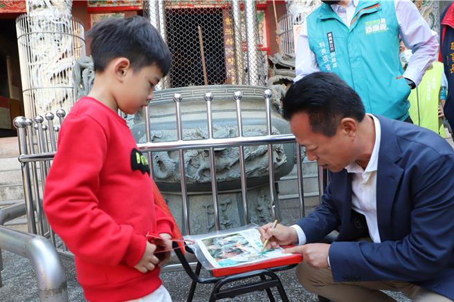 嘉義縣長翁章梁到大埔鄉發龍年紅包，這名男孩加碼索取簽名。（廖素慧攝）