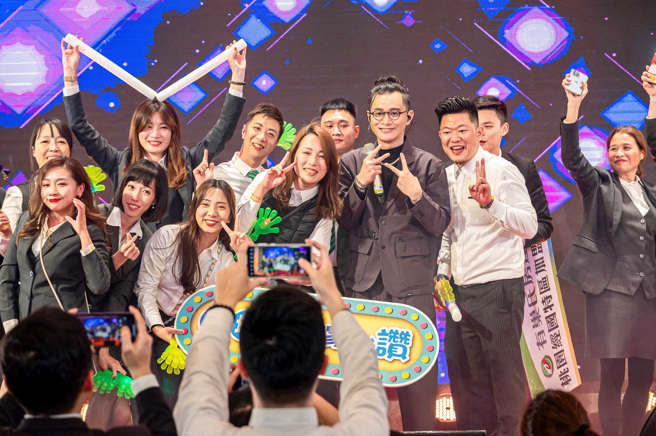 有巢氏房屋桃園尾牙請到唱匠卓義峰，同仁爭相上台合影留念。(圖/永慶房產集團提供)