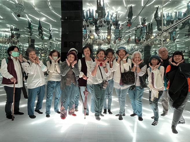 台中市31位平均年龄80岁的长者日前到大里艺术广场的「异想新乐园」畅玩，在光彩绚丽的灯墙前化身不老「网美」、「网帅」拍美照，一圆春节前夕「不老乐园梦」。（中阳集团提供／潘虹恩台中传真）