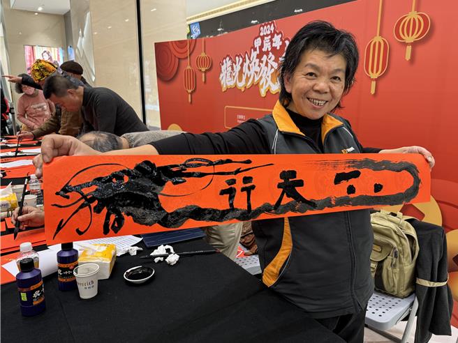 金门文艺学会理事长张君玉开心展示帮民眾刚写好「热腾腾」的喜庆春联。(于家麒摄)