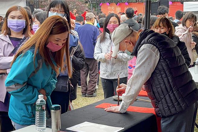 竹北乐龙龙年货大街3日开幕，现场有大师挥毫送春联活动。（罗浚滨摄）