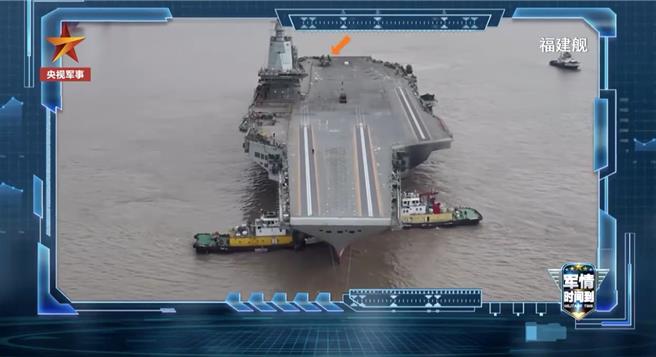 央视新闻近日披露大陆国产航空母舰福建舰侧面全身照，可以看到舰尾停放一架折起机翼的「舰载机」模型。（橘色箭头标示处，央视新闻）