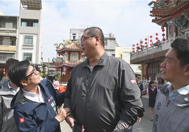 高雄市长陈其迈（前左）5日到楠梓区凤屏宫发放小红包，一名身高200公分左右的支持者吴先生（前中）与陈其迈逗趣拍照。（林瑞益摄）