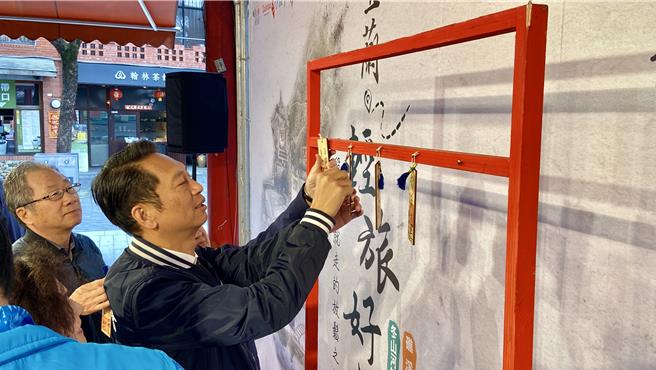 宜兰县议会议长张胜德示范将祈愿卡挂在祈愿墙上。（吴佩蓉摄）
