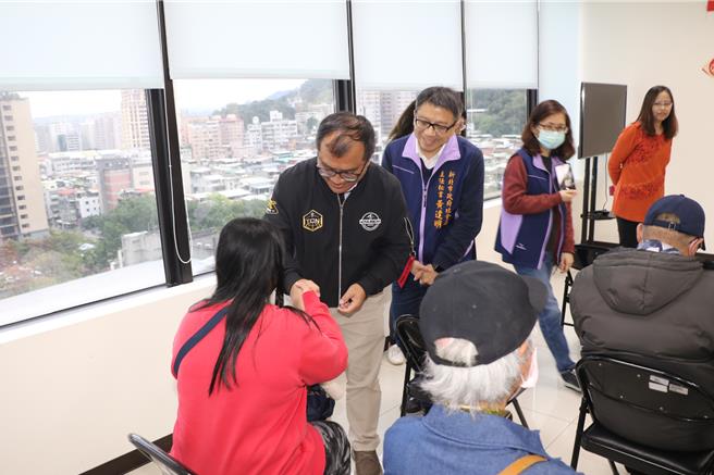 ：新北市新希望基金会主任林约瑟（中）和黄逢明（后）致赠3千元红包给弱势户。（新北市社会局提供）