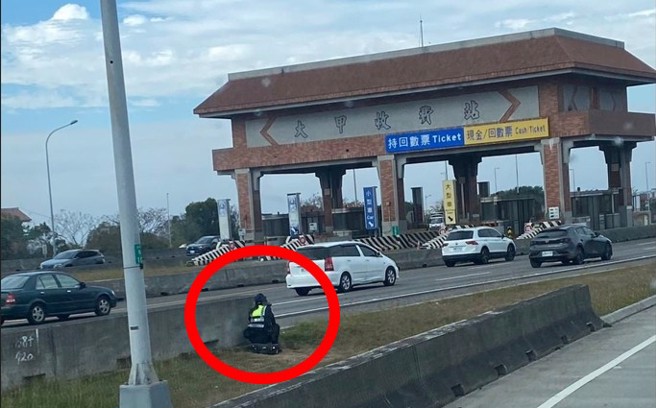 国道马尾女警蹲在护栏外，手持测速枪在抓民眾开车超速。 （民眾提供）