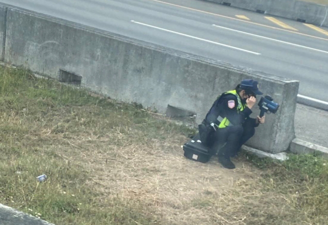 国道马尾女警蹲在护栏外，手持测速枪在抓民眾开车超速。 （民眾提供）