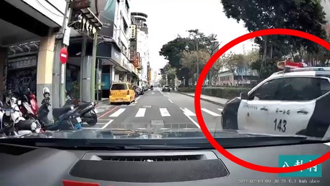 台中市警局第一分局的警车，有亮警示灯，行人等警车通过后才过马路。（翻摄脸书八卦村 - 行车纪录器影片上传中心）
