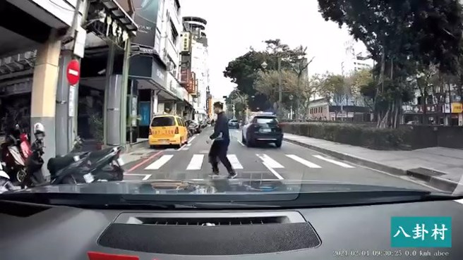 台中市警局第一分局的警车，有亮警示灯，行人等警车通过后才过马路。（翻摄脸书八卦村 - 行车纪录器影片上传中心）