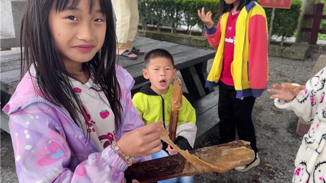 台东县鹿野乡永安村秉持传统方式制作年糕，迄今已23年，孩子开心品尝搅拌棒上剩余的年糕。（蔡旻妤摄）