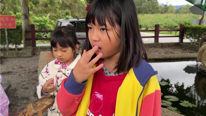 台东县鹿野乡永安村秉持传统方式制作年糕，迄今已23年，孩子开心品尝搅拌棒上剩余的年糕。（蔡旻妤摄）