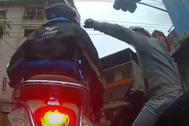 有2騎士在等紅燈時爆發口角，沒想到1名騎士於爭執中，拿出辣椒水偷襲，噴完後便烙跑，但疑似天雨路滑關係，這名騎士壓到水溝蓋摔車。（ 圖／ 翻攝自「WoWtchout-地圖型行車影像分享平台」）