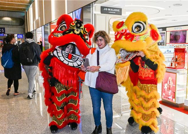 恒昌免税店7日在桃园国际机场第二航厦中央区出境大厅，安排舞狮绕场表演展示吉祥话，以及财神爷发放糖果，与出国旅客同欢，不少旅客抢着与财神爷拍照，搭配着「新年快乐」、「财源滚滚」手举牌，让游客在春节前夕就能感受浓厚年味。（陈麒全摄）