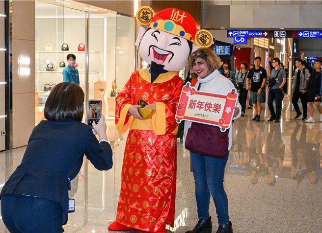 恒昌免税店7日在桃园国际机场第二航厦中央区出境大厅，安排舞狮绕场表演展示吉祥话，以及财神爷发放糖果，与出国旅客同欢，不少旅客抢着与财神爷拍照，搭配着「新年快乐」、「财源滚滚」手举牌，让游客在春节前夕就能感受浓厚年味。（陈麒全摄）