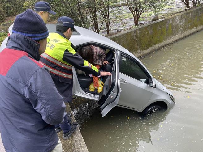 天雨視線不佳，老婦把車開進排水溝，警協助她爬出車外。(警方提供／呂筱蟬桃園傳真)