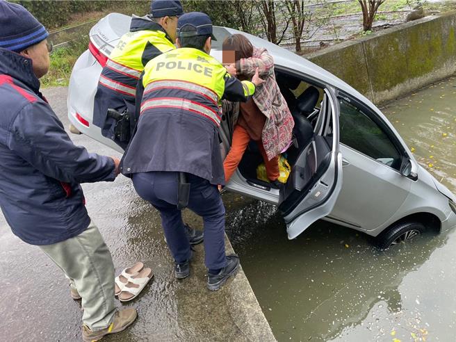 天雨視線不佳，老婦把車開進排水溝，警協助她爬出車外。(警方提供／呂筱蟬桃園傳真)