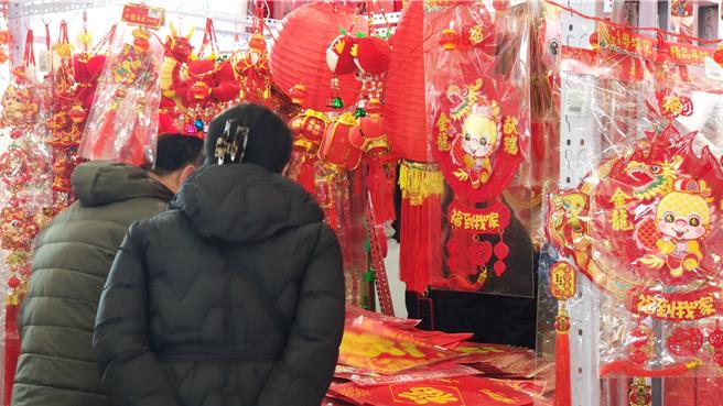 北京年货大集吸引不少人前往，纷纷买起龙年喜庆的挂件饰品与春联，等着增添新年喜气。（吴泓勋摄）