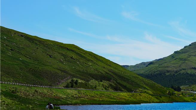 在天无三日晴的苏格兰，享受阳光洒满起伏山峦、蓝天白云飘浮无边天际、清风徐徐轻抚无尽笑意脸颊的畅快，即便所在的位置只是路边一小块避车空间。（王爵暐摄）