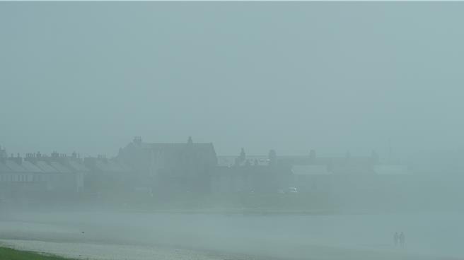 初登岛的时分，浓雾还未全然散去，飘渺间，人影依稀漫步海滩，分不清真实与虚幻的界线。（王爵暐摄）