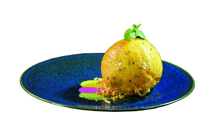 〈手工酥炸冰淇淋〉外層是球形磅蛋糕，內餡是香草冰淇淋，沾裹以椰奶、芝麻及椰子粉、在來米粉、樹薯粉等製成的酥炸粉一同油炸，再淋上香甜蜂蜜及腰果碎。圖／姚舜