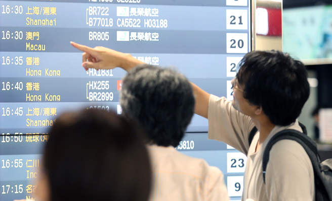 图为桃园机场第二航厦出境大厅内，旅客正在查看班机时刻表。（资料照，范扬光摄）