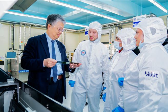 英国斯特普尼诸圣中学访问团21日参访明新科大半导体人才培育基地，校长刘国伟（左）解说半导体封装制程与设备运作。（罗浚滨摄）