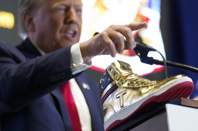 川普17日在費城亮出一雙原價399美元的限量版金色高筒運動鞋募款。（美聯社）