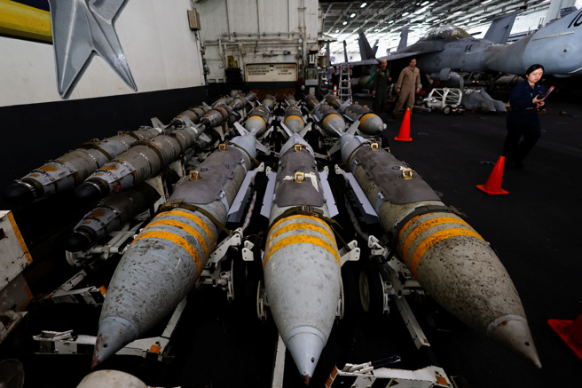 2024年2月13日，红海南部，美国海军工作人员在艾森豪号航空母舰 (CVN 69) 机库旁的航空炸弹旁。（路透社）