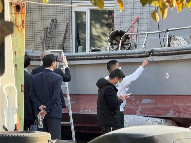 陆方人员与家属都拿起手机拍照、录影，查看船体有无撞击之痕迹，甚至还登上渔船，发现可疑之处还拿出卷尺、甚至以指幅进行丈量。(于家麒摄)