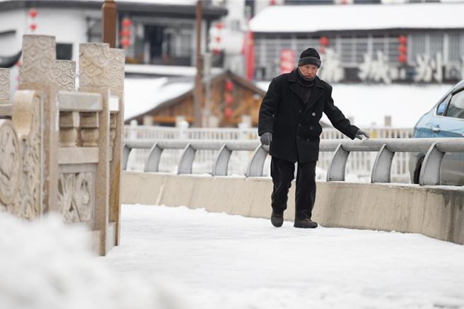 圖為湖南省張家界23日雨雪冰凍天氣持續，市民緩慢行走在街頭。（中新社資料照片）
