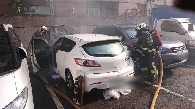 新北市三峡区大德路一处私人停车场内，15年的老车引擎突冒黑烟窜火。（新北市消防局第五大队提供／刘玮晴新北传真）