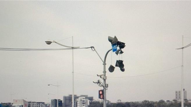 台中市37歲陳姓男子26日中午12點多駕駛砂石車行經太平區太堤東路與工業17路口時，車輛附載之拖車防塵網不慎碰撞路口紅綠燈，造成紅綠燈受損，數顆燈號就垂掛在燈柱上搖搖欲墜。（民眾提供／潘虹恩台中傳真）