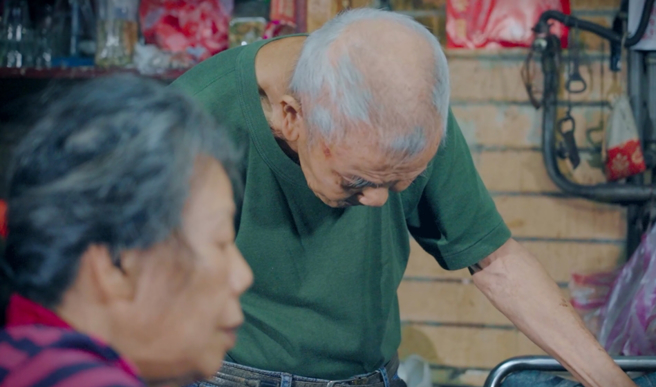 万华「盆栽爷爷」(图后)照顾瘫痪妻，摆摊卖盆栽扛家计。(吴振煌拍摄)