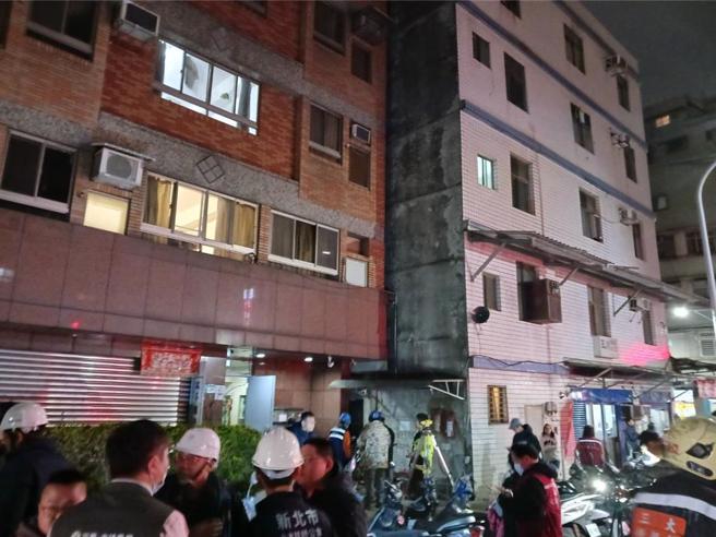 新北市三重区福隆路的新建工地疑似进行地基工程，造成左方公寓向右倾斜。（新北消防局提供／张铠乙新北传真）