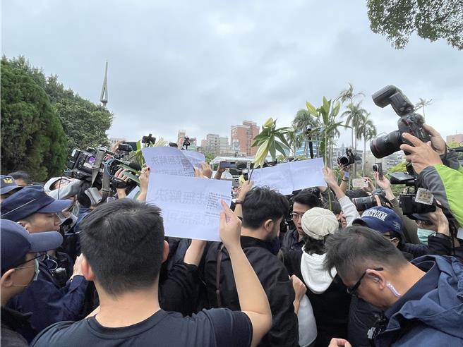 「無力者」今則在二二八事件追思會場入口歌唱、舉牌抗議。（蔡佩珈攝）