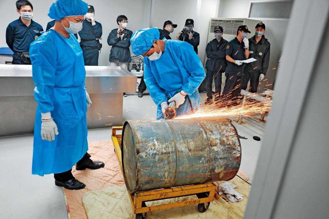 陈男被水泥封在铁桶内，鑑识人员必须使用电锯才能开桶验尸。（图／翻摄画面）