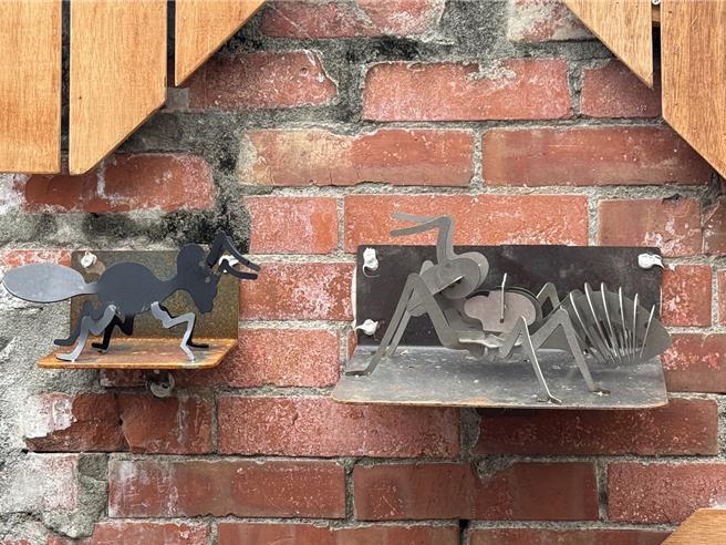 台中市太平區「太和宮藝文曲巷」近日引入勤益科技大學學生的鐵雕作品，包括蜻蜓、螞蟻、花朵等鐵工創作點綴巷弄。（潘虹恩攝）