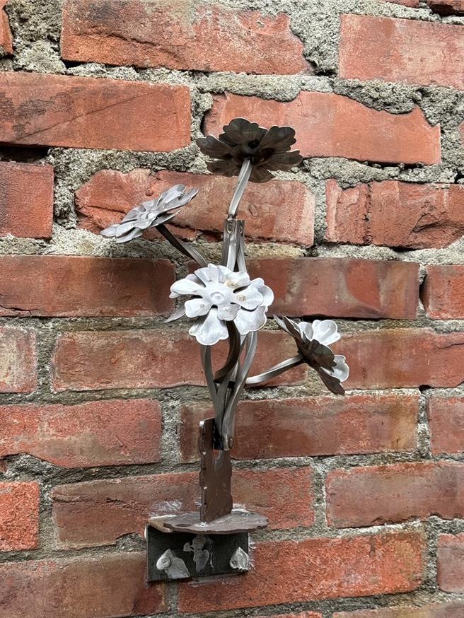 台中市太平區「太和宮藝文曲巷」近日引入勤益科技大學學生的鐵雕作品，包括蜻蜓、螞蟻、花朵等鐵工創作點綴巷弄。（潘虹恩攝）