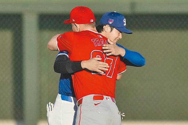 加盟道奇的大谷翔平（後）與天使前隊友卓奧特在熱身賽前擁抱寒暄。（美聯社）